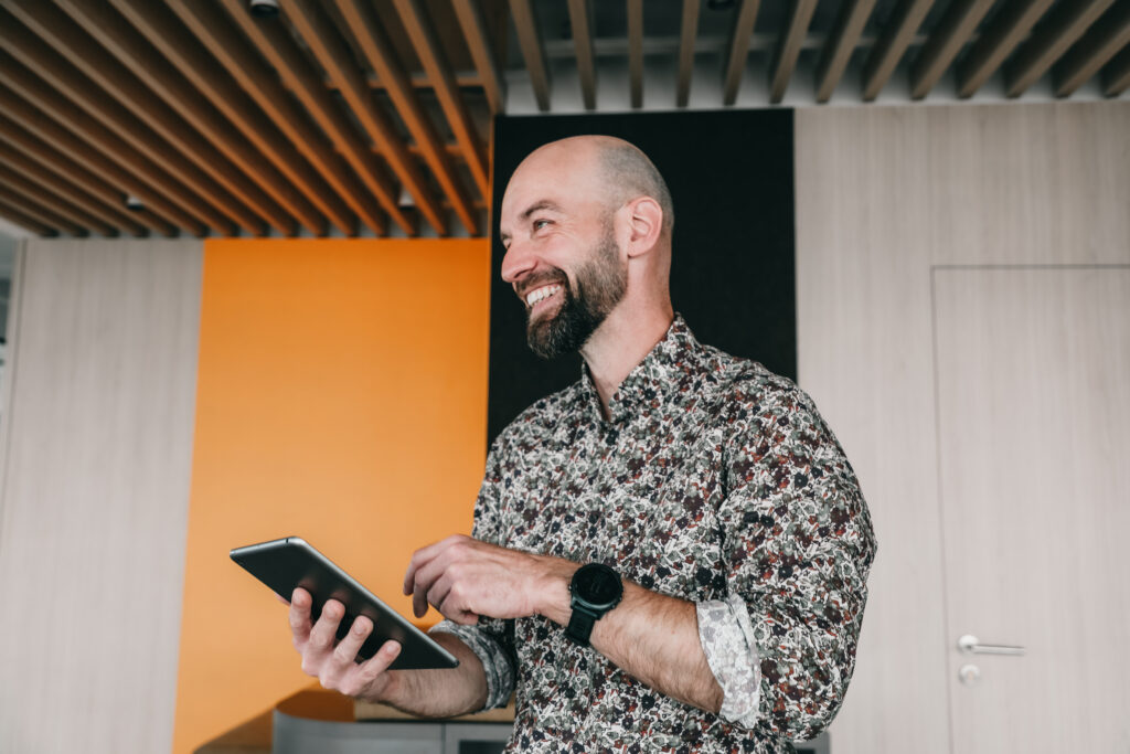 man in the office smiling holding a tablet