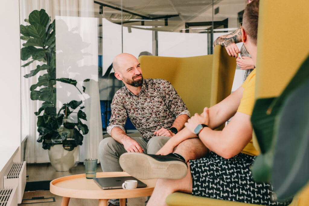 man in a yellow chair talking to his colleagues