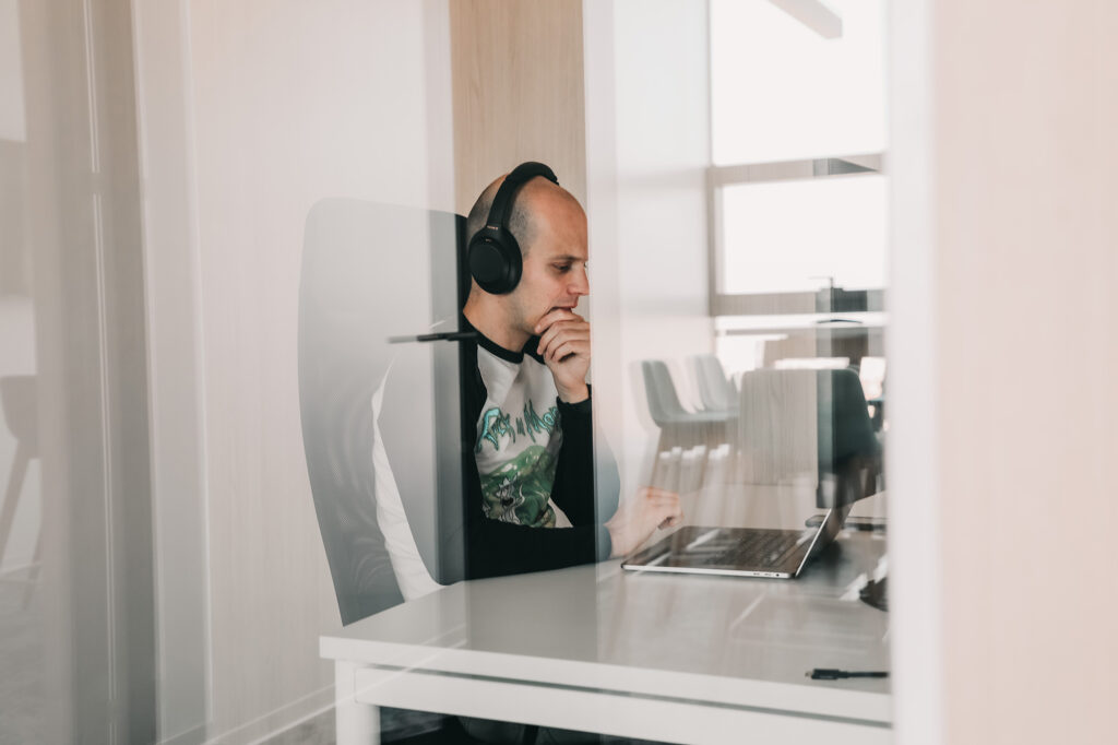 a male software engineer working on a laptop with headphones on