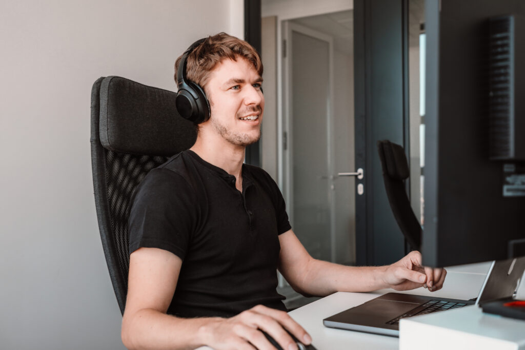 a male data engineer working on his laptop with headphones on