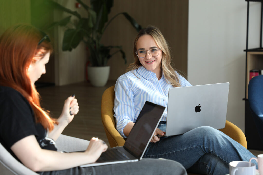 two female colleagues talking with laptops on their knees