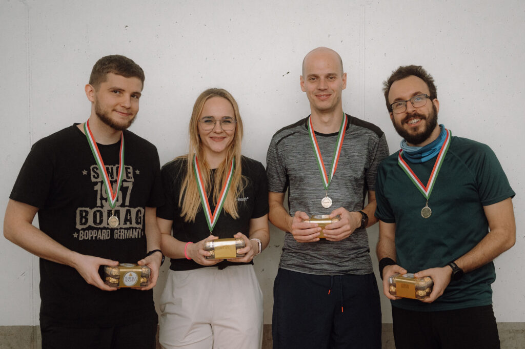 three male and one female colleague holding trophies after a team building